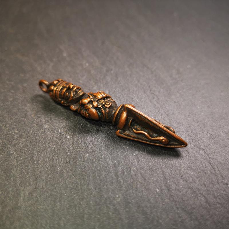 This vintage Phurba pendant was collected from Rega Monastery(Baiyu,Tibet),handmade of copper. It has a statue of Vajrapani on the top and a phurba on the lower part, measuring about 2.36 inches by 0.47 inch.