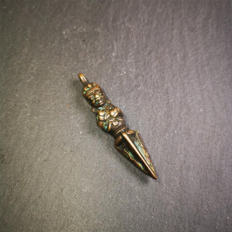 This vintage Phurba pendant was collected from Rega Monastery(Baiyu,Tibet),handmade of copper. It has a statue of Vajrapani on the top and a phurba on the lower part, measuring about 2.36 inches by 0.47 inch.