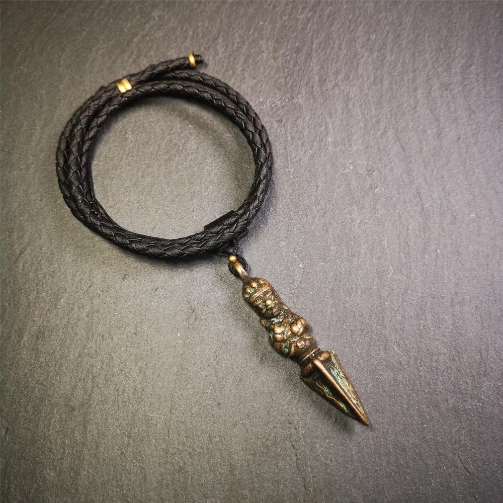 This vintage Phurba pendant was collected from Rega Monastery(Baiyu,Tibet),handmade of copper. It has a statue of Vajrapani on the top and a phurba on the lower part, measuring about 2.36 inches by 0.47 inch.