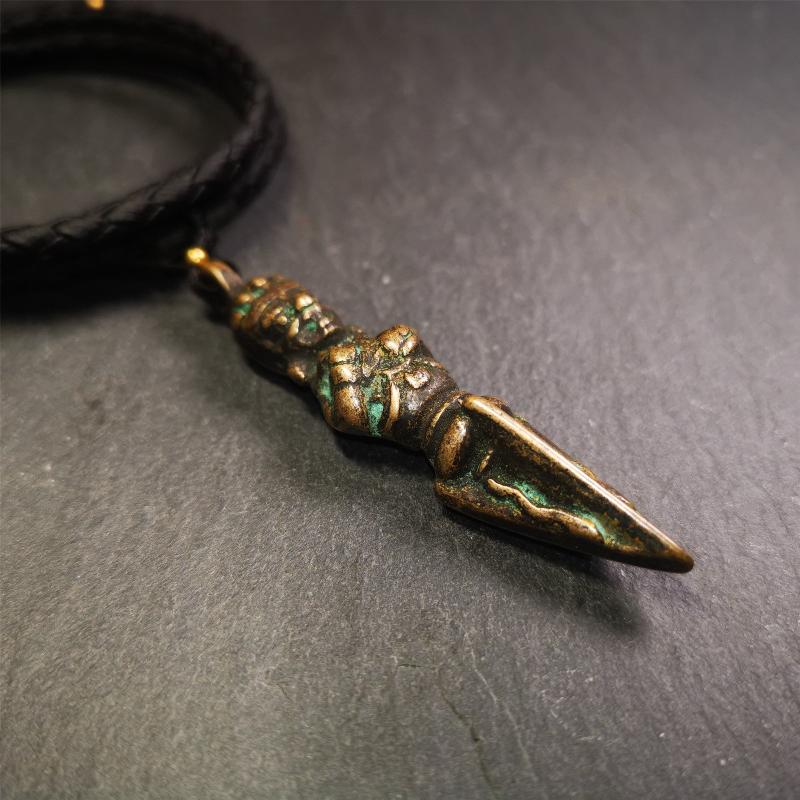 This vintage Phurba pendant was collected from Rega Monastery(Baiyu,Tibet),handmade of copper. It has a statue of Vajrapani on the top and a phurba on the lower part, measuring about 2.36 inches by 0.47 inch.
