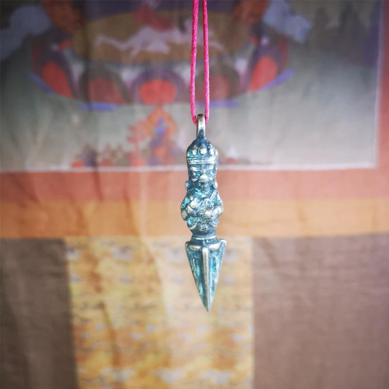 This vintage Phurba pendant was collected from Rega Monastery(Baiyu,Tibet),handmade of copper. It has a statue of Vajrapani on the top and a phurba on the lower part, measuring about 2.36 inches by 0.47 inch.