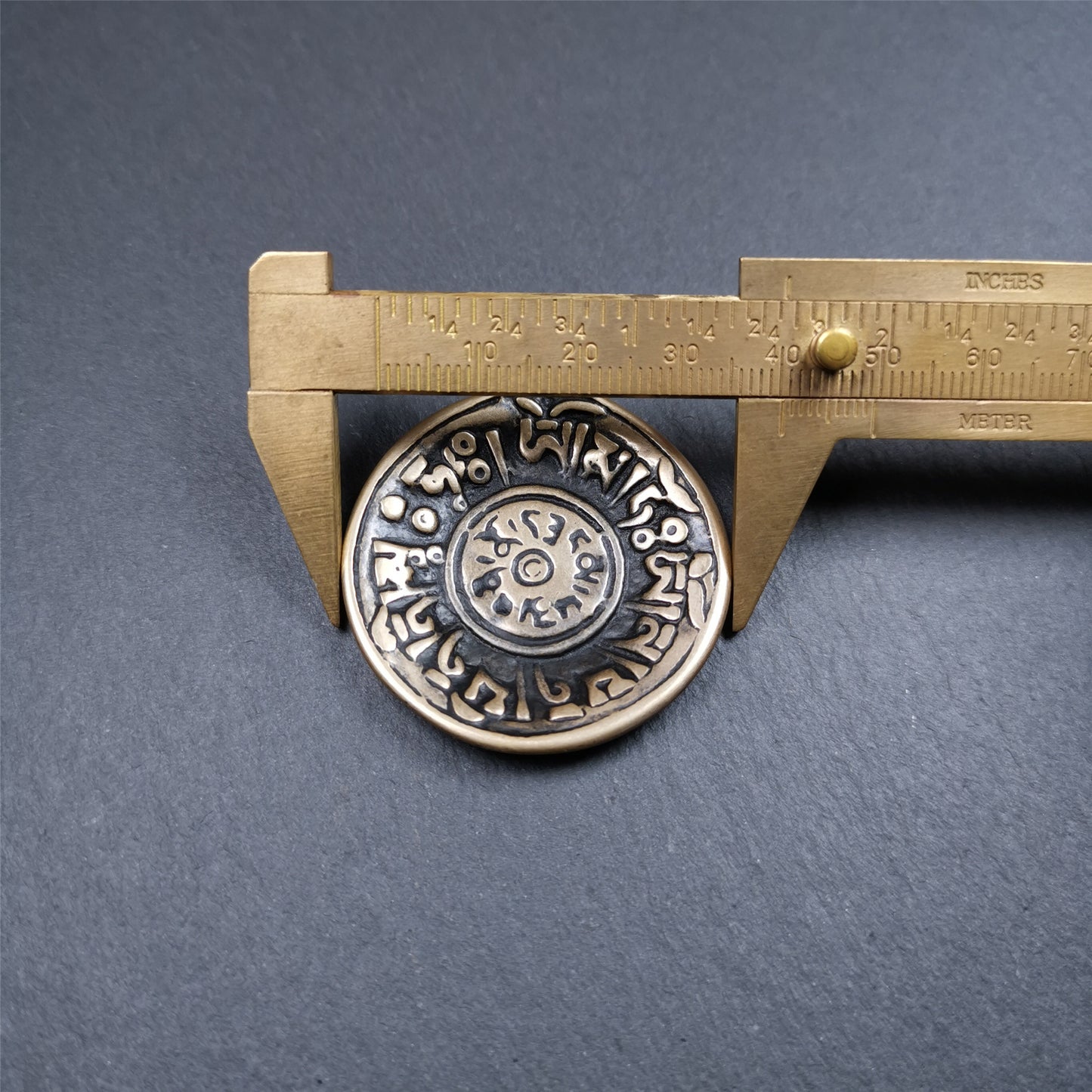 This Om badge amulet was collected from Yushu City Tibet,about 50 years old. It is round shape,made of lima brass, 1.58 inches,carved with mantra of chenrezig OM MANI PADME HUM. You can make it into a necklace, or a keychain, pendant