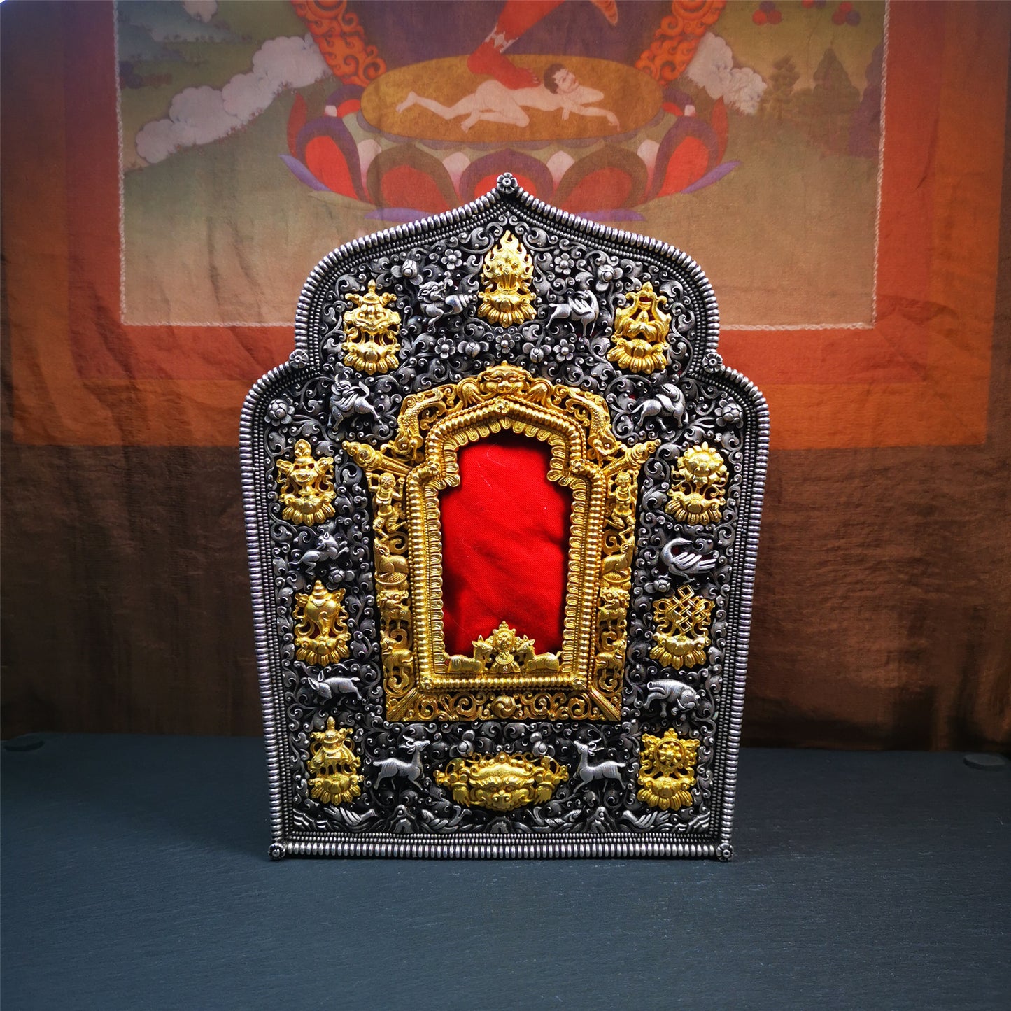 This large Gau shrine was handcrafted by Tibetan artisans from Hepo Township, Baiyu County. Each exquisite pattern on it is meticulously hand-carved,and it is embellished with the technique of gold inlay, with pure silver inlaid on the red copper material and gold-plated on the pure silver material.Its theme is Astamangala, and it features 10 mythical creatures traversing a silver-patterned meadow. The interior space of the box is quite spacious, large enough to accommodate a 12 * 8 cm Buddha statue.