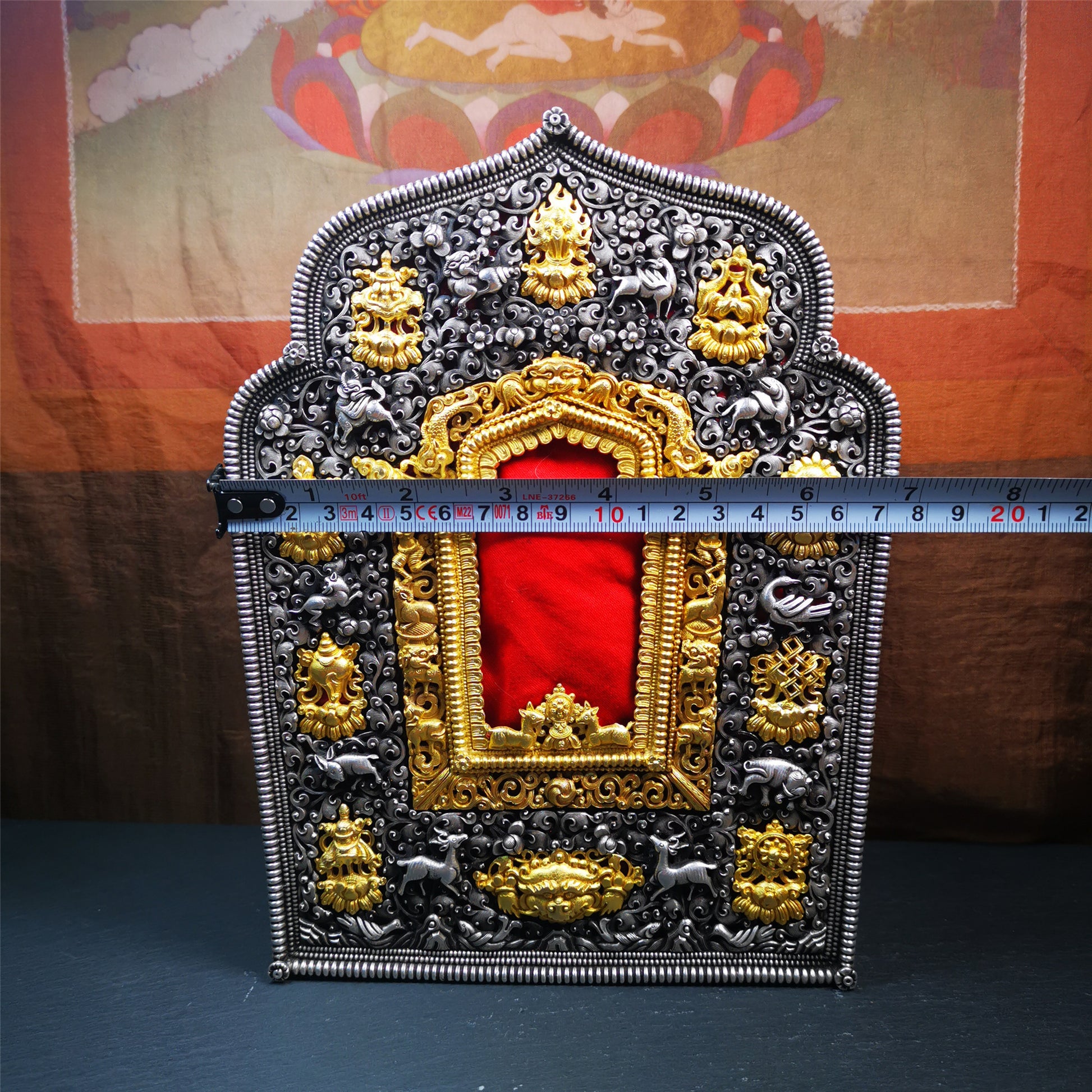This large Gau shrine was handcrafted by Tibetan artisans from Hepo Township, Baiyu County. Each exquisite pattern on it is meticulously hand-carved,and it is embellished with the technique of gold inlay, with pure silver inlaid on the red copper material and gold-plated on the pure silver material.Its theme is Astamangala, and it features 10 mythical creatures traversing a silver-patterned meadow. The interior space of the box is quite spacious, large enough to accommodate a 12 * 8 cm Buddha statue.