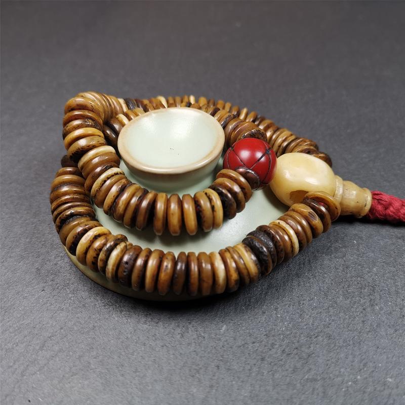 This bone carved mala beads is made by Tibetan craftsmen,about 30 years Old. It has 108 flat shape beads,1 red plastic spacer bead,and 1 yak bone guru bead,all hand carved,diameter is 12mm and perimeter is 15".
