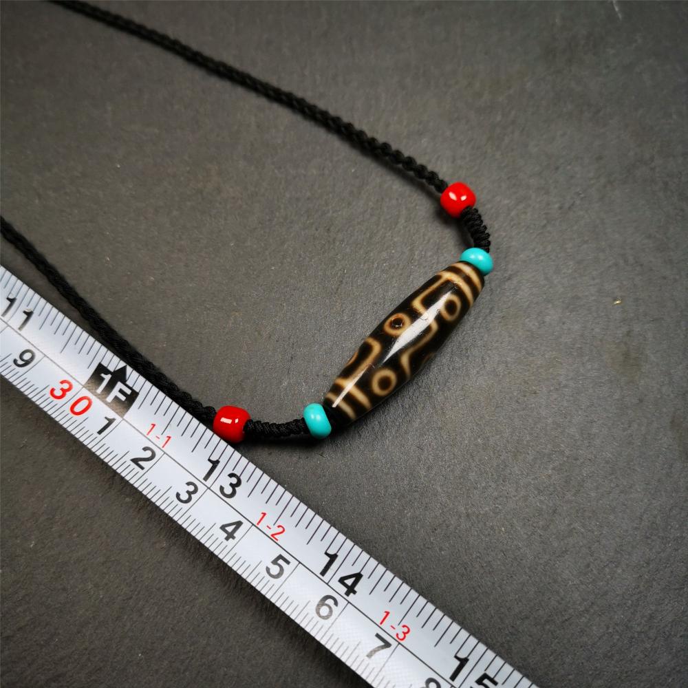 This 9 eyes dzi bead was collected from gerze Tibet,about 40 years old. The necklace was hand-woven by Tibetans from Baiyu County, the main bead is a brown color 9 eyes dzi, paired with 2 turquoise beads and 2 red agate beads.