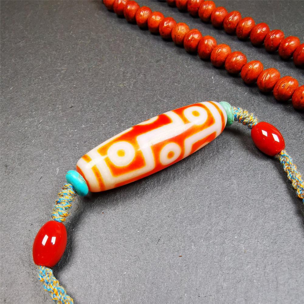 This necklace was hand-woven by Tibetans from Baiyu County, the main bead is a fire agate 9 eyes dzi, paired with 2 turquoise beads and 2 red agate beads,about 30 years old. The length of the necklace can be adjusted, the maximum circumference is about 60cm.