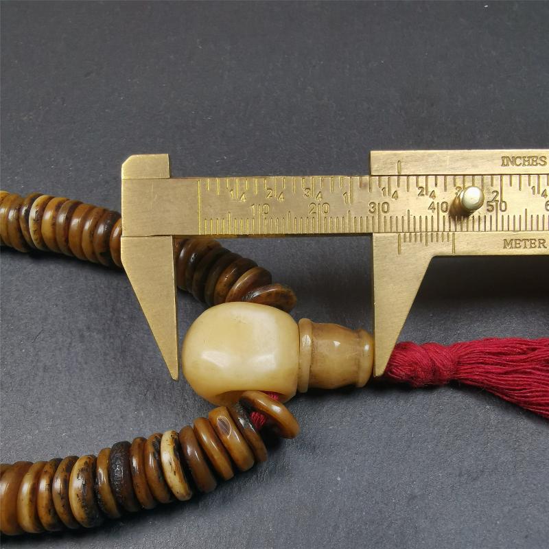 This bone carved mala beads is made by Tibetan craftsmen,about 30 years Old. It has 108 flat shape beads,1 red plastic spacer bead,and 1 yak bone guru bead,all hand carved,diameter is 12mm and perimeter is 15".