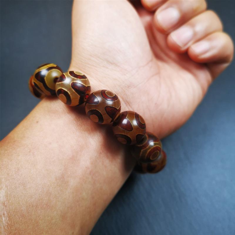 This 3 eyes bracelet was hand-woven by Tibetans,It's made of 3 eyes round dzi beads,brown color,diameter is 0.63", the circumference of bracelet is 7.5". It can be worn not only as a fashionable accessory but also holds cultural and religious significance.