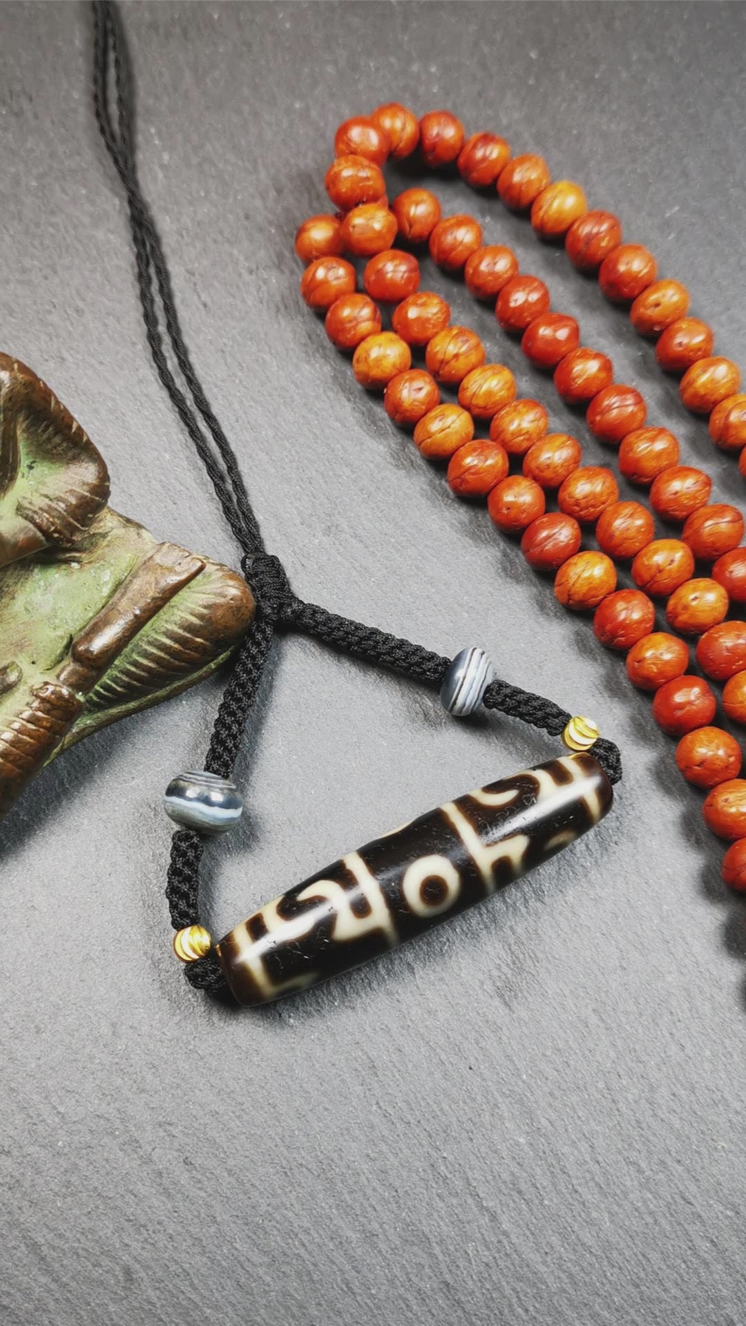 This necklace was hand-woven by Tibetans from Baiyu County, the main bead is a Guru Rinpoche's Ritual Paraphernalia Dzi bead, paired with 2 small stripe dzi beads,about 40 years old. It can be worn not only as a fashionable accessory but also holds cultural and religious significance. The length of the necklace can be adjusted, the maximum circumference is about 60cm.