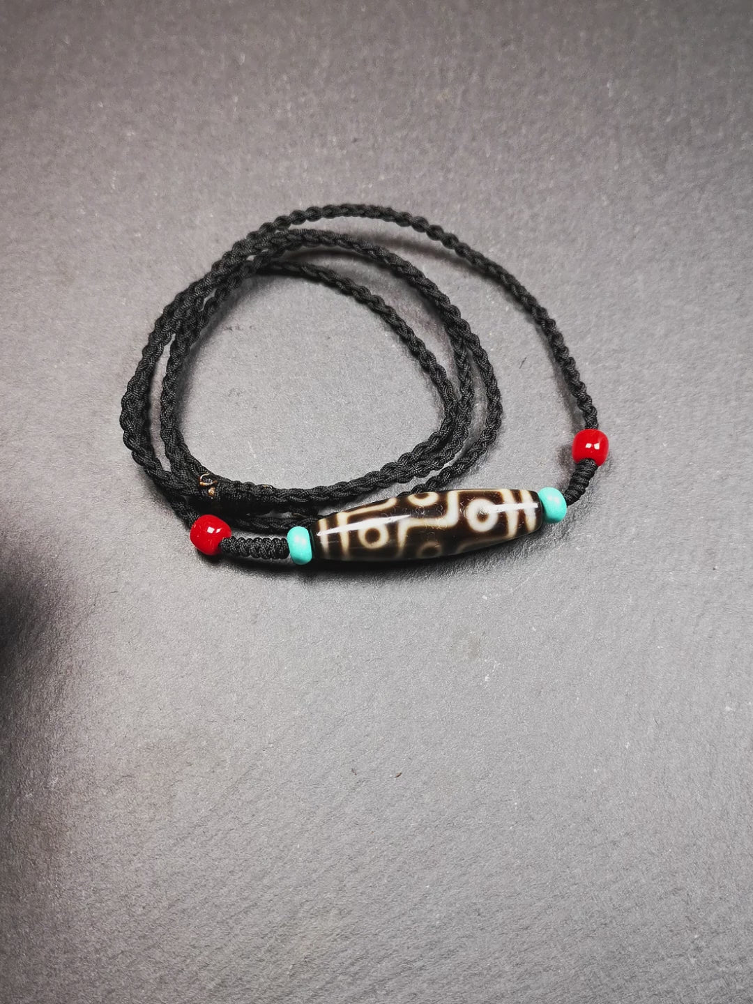 This 9 eyes dzi bead was collected from gerze Tibet,about 40 years old. The necklace was hand-woven by Tibetans from Baiyu County, the main bead is a brown color 9 eyes dzi, paired with 2 turquoise beads and 2 red agate beads.