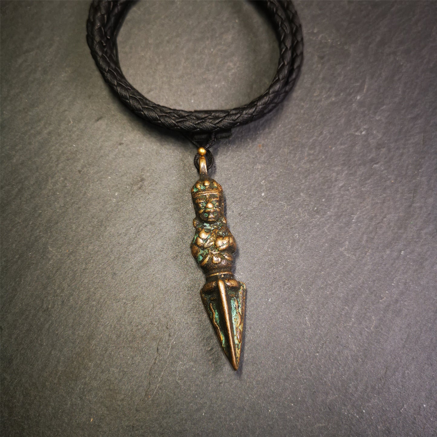 This vintage Phurba pendant was collected from Rega Monastery(Baiyu,Tibet),handmade of copper. It has a statue of Vajrapani on the top and a phurba on the lower part, measuring about 2.36 inches by 0.47 inch.