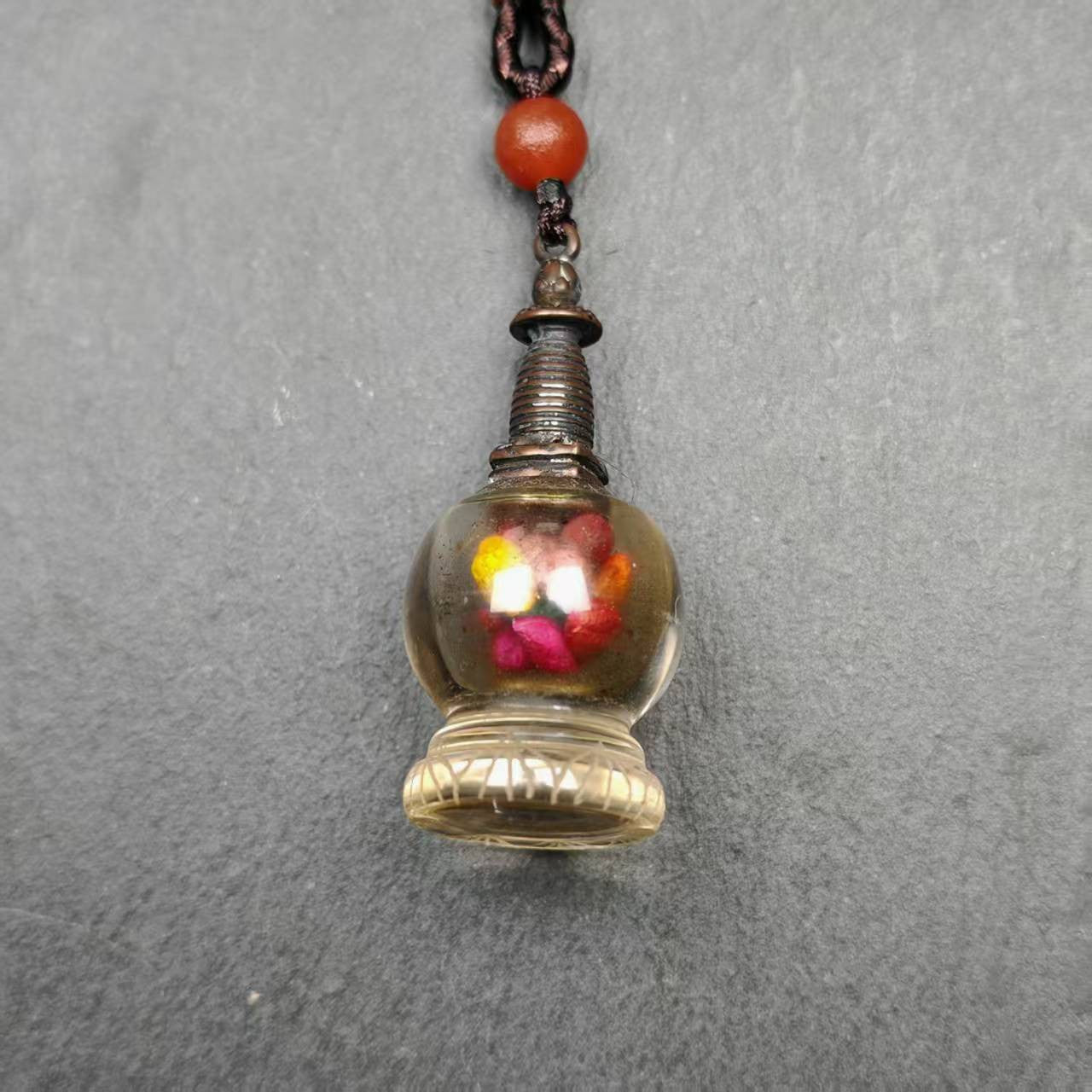 This crystal stupa was hand carved by Tibetan craftsmen from Tibet in 1990s,fulfilled consecrations and blessed in Kathok monastery.
Its lid is metal and body is crystal, the lid can be opened and you can place offerings inside,like mani rilbu or zung consecration.

You can make it into a necklace, or put it in your shrine / altar.