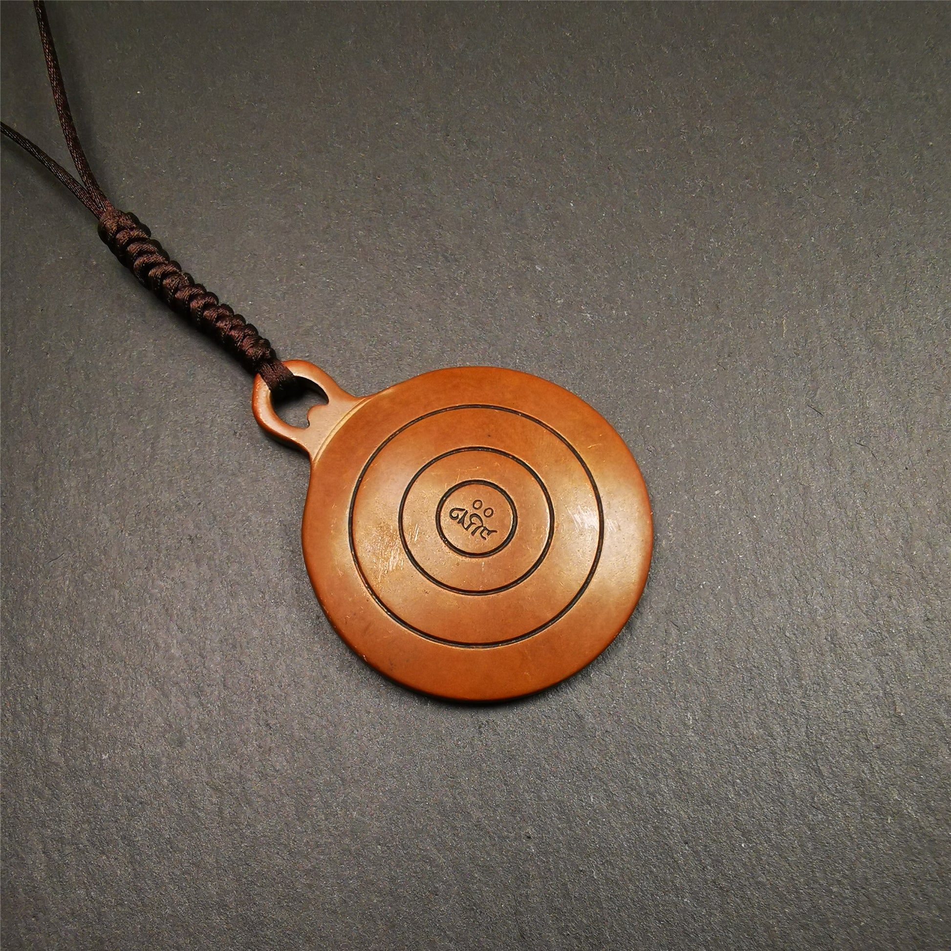 This OM badge amulet was collected from Jiegu Monastery Tibet.It is made of copper,diameter is 1.65 inches,Chenrezig is on the center, carved with Tibetan Letter ,Om Mani Padme Hum mantra,the letter on the back is Mind
