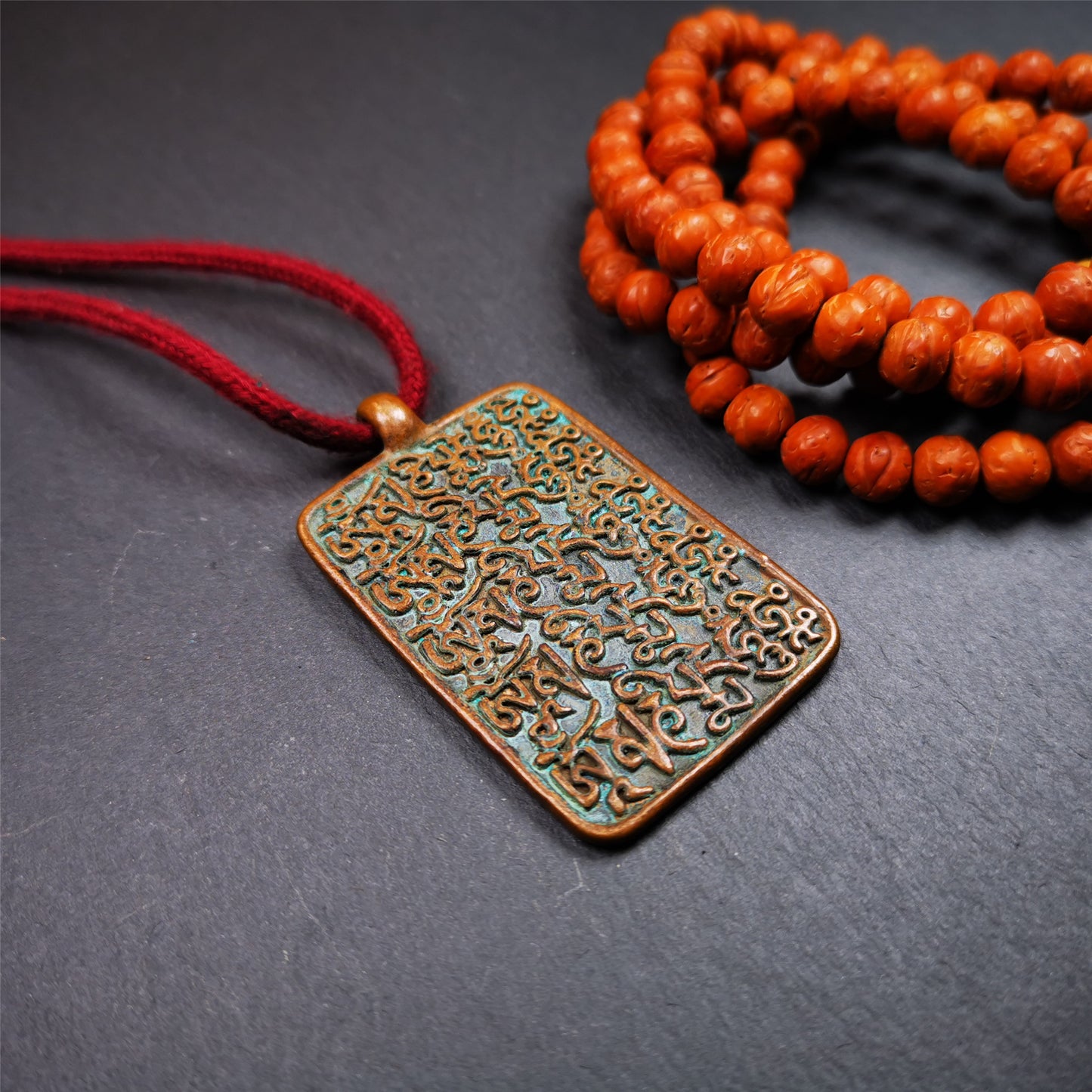 This badge is made by Tibetan craftsmen from Hepo Town, Baiyu County, the birthplace of the famous Tibetan handicrafts. It is made of copper, 2.44 × 1.42 inches. The front is the OM mantra and the back is body, speech, and mind.