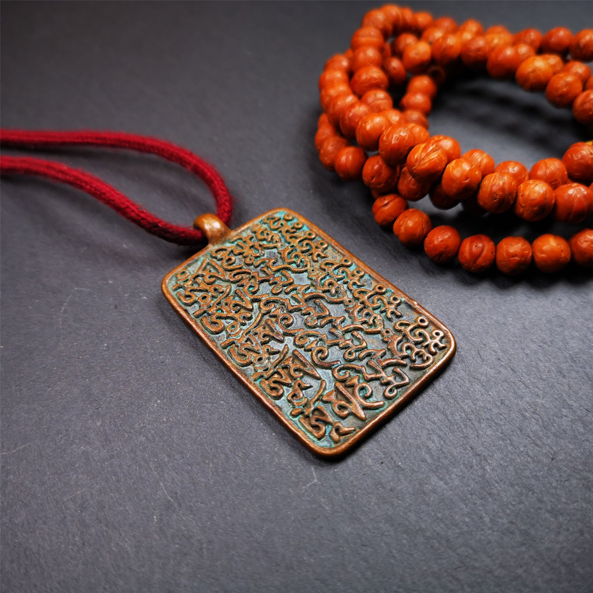 This badge is made by Tibetan craftsmen from Hepo Town, Baiyu County, the birthplace of the famous Tibetan handicrafts. It is made of copper, 2.44 × 1.42 inches. The front is the OM mantra and the back is body, speech, and mind.