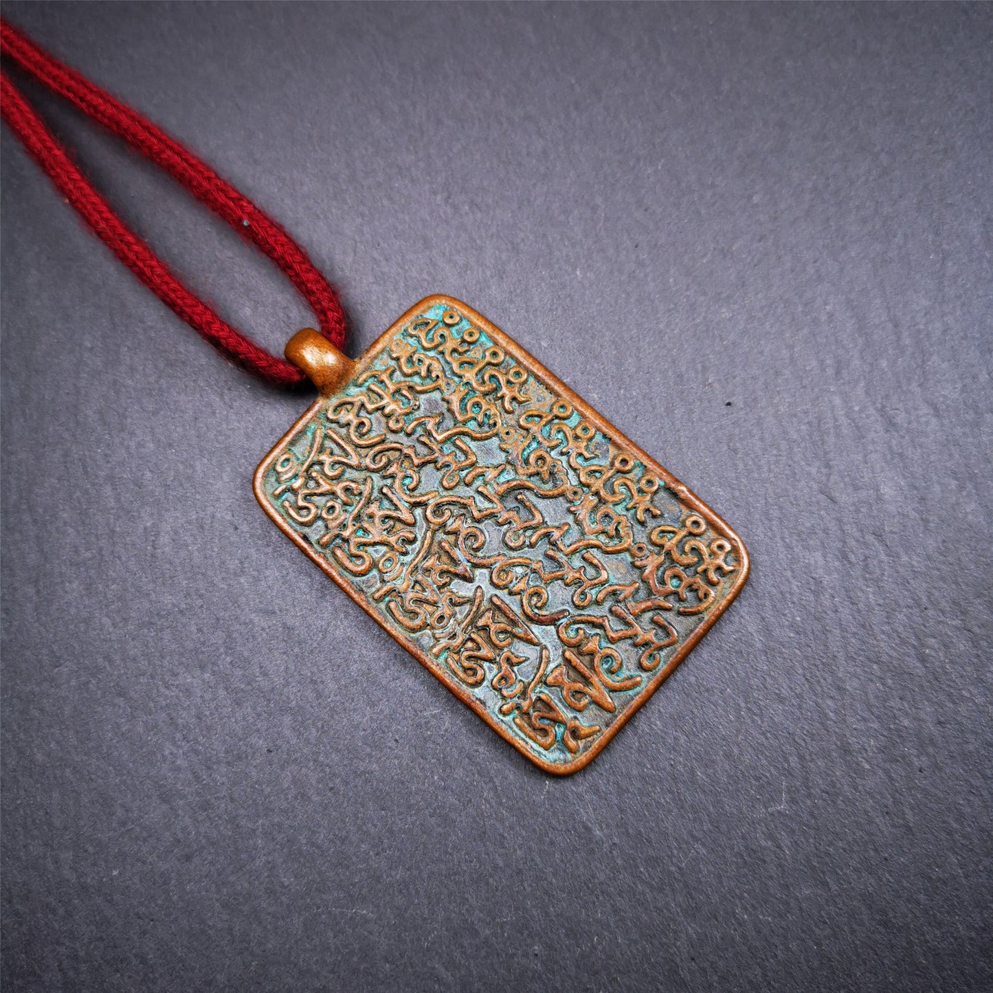 This badge is made by Tibetan craftsmen from Hepo Town, Baiyu County, the birthplace of the famous Tibetan handicrafts. It is made of copper, 2.44 × 1.42 inches. The front is the OM mantra and the back is body, speech, and mind.