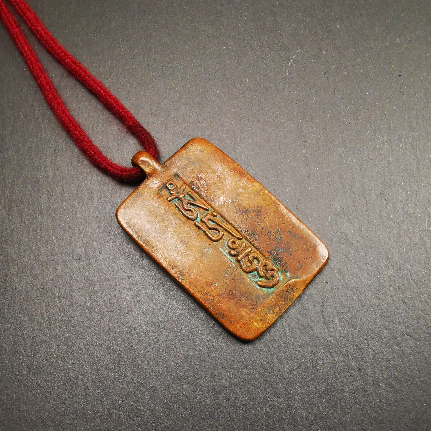 This badge is made by Tibetan craftsmen from Hepo Town, Baiyu County, the birthplace of the famous Tibetan handicrafts. It is made of copper, 2.44 × 1.42 inches. The front is the OM mantra and the back is body, speech, and mind.