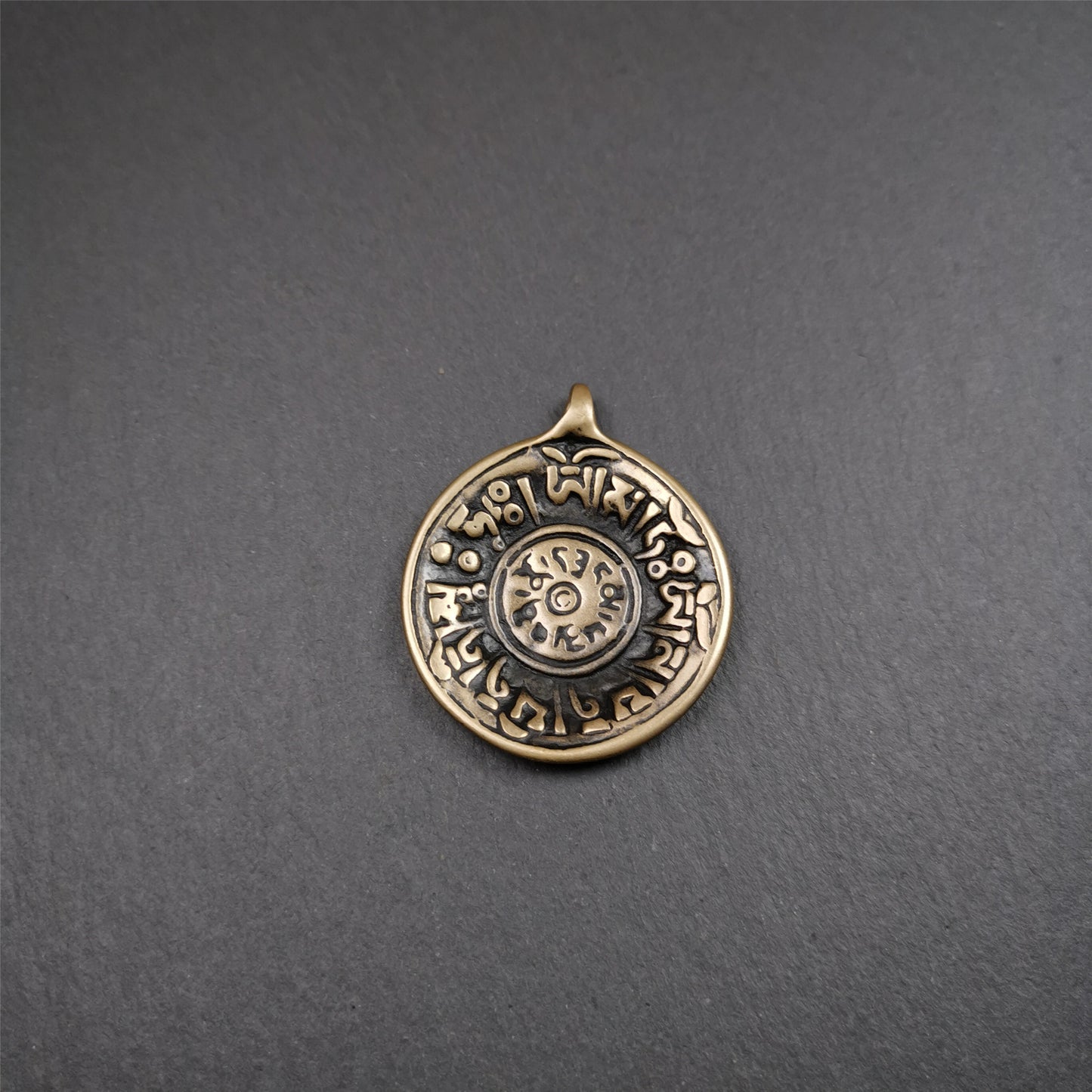 This Om badge amulet was collected from Yushu City Tibet,about 50 years old. It is round shape,made of lima brass, 1.58 inches,carved with mantra of chenrezig OM MANI PADME HUM. You can make it into a necklace, or a keychain, pendant