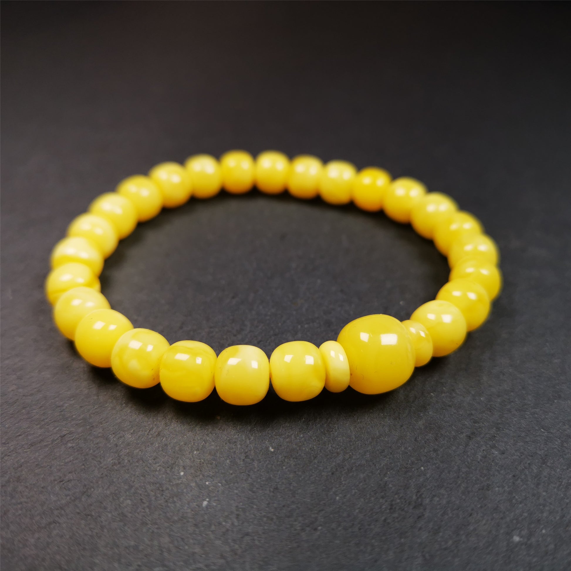 This amber beads bracelet was hand-woven by Tibetans from Baiyu County,Tibet. It is made of amber, yellow color,consists 1 main bead,25 small beads and 2 spacer beads,tie with elastic cord to fit your wrist.