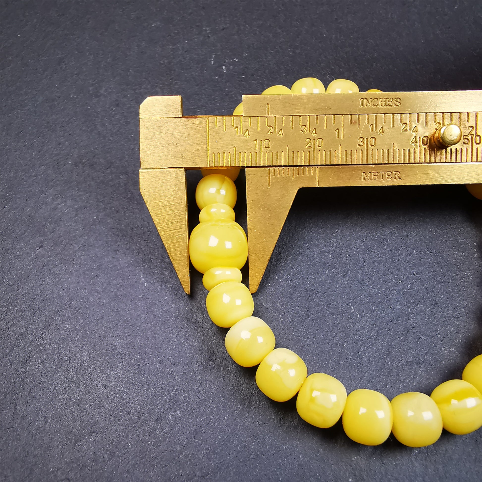 This amber beads bracelet was hand-woven by Tibetans from Baiyu County,Tibet. It is made of amber, yellow color,consists 1 main bead,25 small beads and 2 spacer beads,tie with elastic cord to fit your wrist.