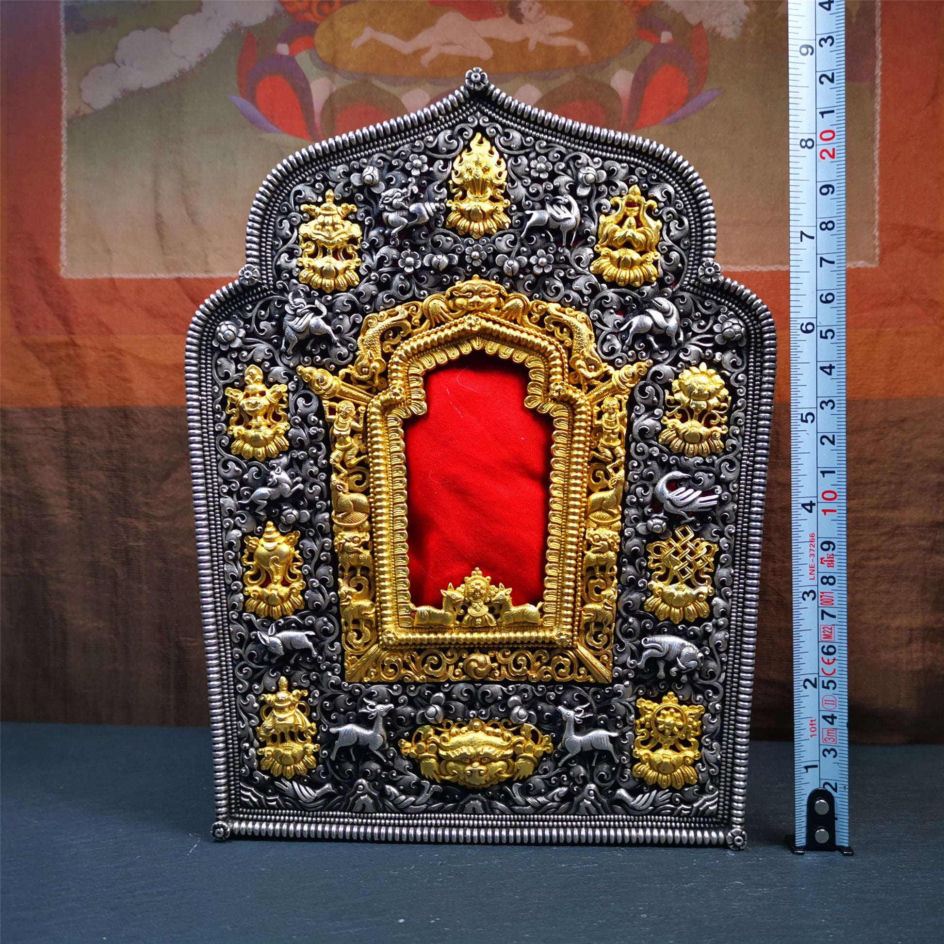 This large Gau shrine was handcrafted by Tibetan artisans from Hepo Township, Baiyu County. Each exquisite pattern on it is meticulously hand-carved,and it is embellished with the technique of gold inlay, with pure silver inlaid on the red copper material and gold-plated on the pure silver material.Its theme is Astamangala, and it features 10 mythical creatures traversing a silver-patterned meadow. The interior space of the box is quite spacious, large enough to accommodate a 12 * 8 cm Buddha statue.