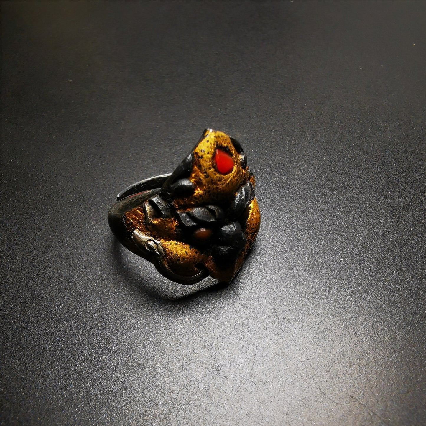 This garuda ring is made by Tibetan craftsmen for 30 years old,and come from Hepo Town, Baiyu County, the birthplace of the famous Tibetan handicrafts.  It is crafted from a variety of materials including solid gold, sterling silver, cold iron, brass and agate,using traditional Tibetan craftsmanship to carry out multiple carvings and gold filled craftsmanship, inlaid with gold, silver, copper on the base of cold iron, together to create a classic image in Buddhism-Garuda-golden winged bird.