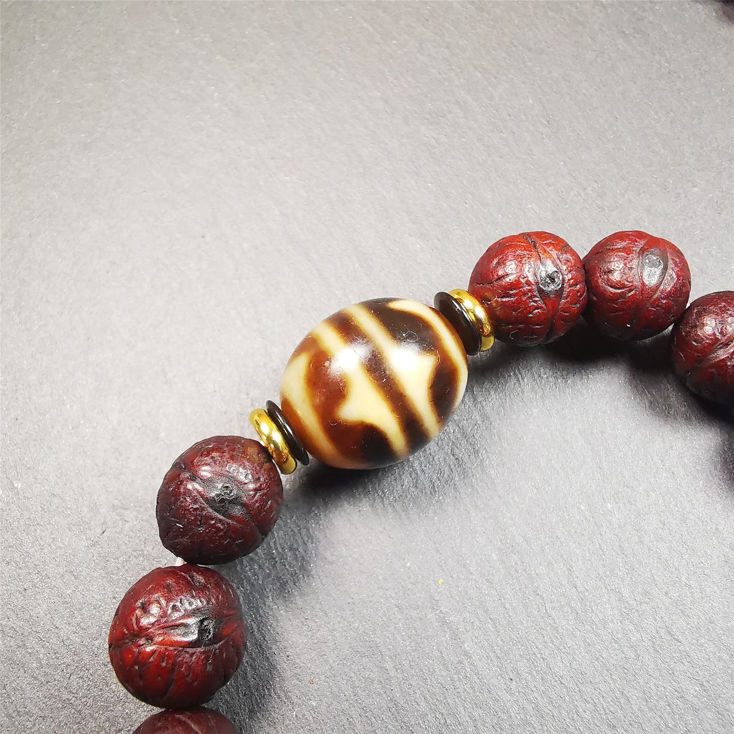 This unique Dalo Dzi bracelet combines the mysterious and unique qualities of the tiger tooth dalo dzi and 15 old bodhi seed beads,giving it a distinct feel.  It is brown in color and has a circumference of approximately 7 inches, suitable for most wrist sizes. 