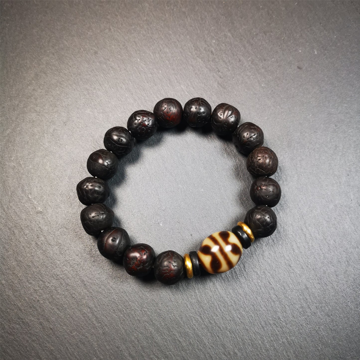 This unique Dalo Dzi bracelet is made up of one tiger tooth Dalo Dzi and 15 old bodhi seed beads. It is brown in color and has a circumference of approximately 7 inches, is suitable for most wrist sizes.  This bracelet combines the mysterious and unique qualities of the tiger tooth Dalo Dzi and the bodhi seed beads, giving it a distinct feel. 