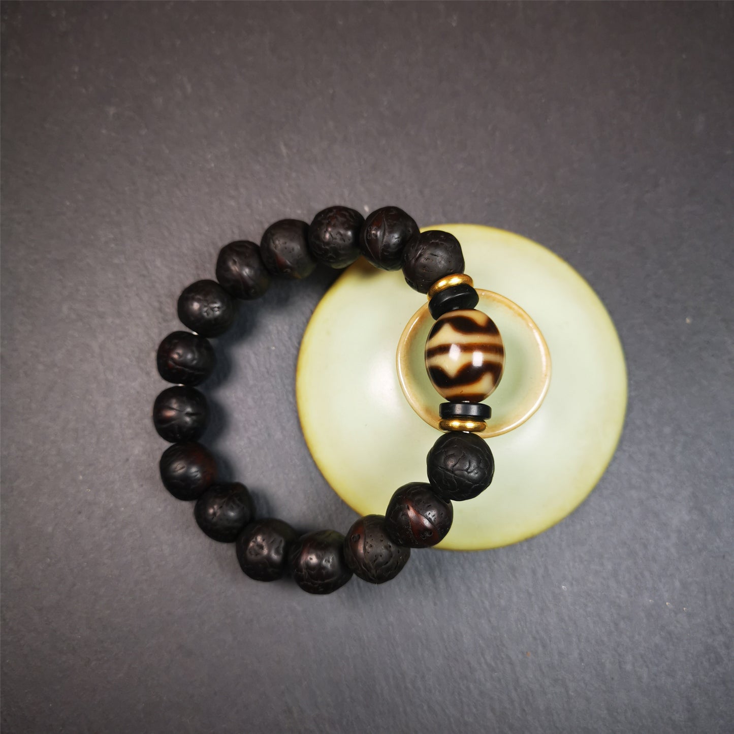 This unique Dalo Dzi bracelet is made up of one tiger tooth Dalo Dzi and 15 old bodhi seed beads. It is brown in color and has a circumference of approximately 7 inches, is suitable for most wrist sizes.  This bracelet combines the mysterious and unique qualities of the tiger tooth Dalo Dzi and the bodhi seed beads, giving it a distinct feel. 