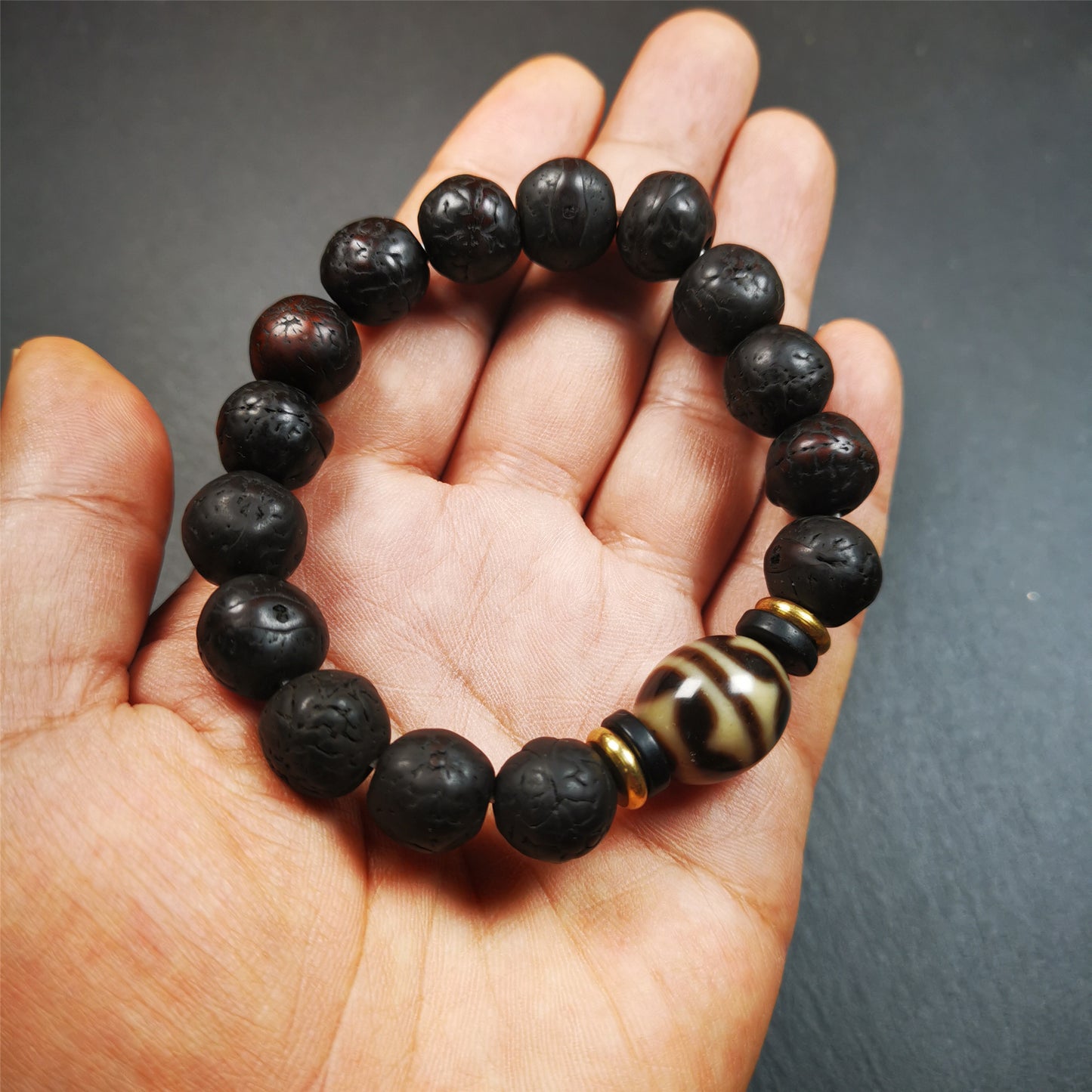 This unique Dalo Dzi bracelet is made up of one tiger tooth Dalo Dzi and 15 old bodhi seed beads. It is brown in color and has a circumference of approximately 7 inches, is suitable for most wrist sizes.  This bracelet combines the mysterious and unique qualities of the tiger tooth Dalo Dzi and the bodhi seed beads, giving it a distinct feel. 