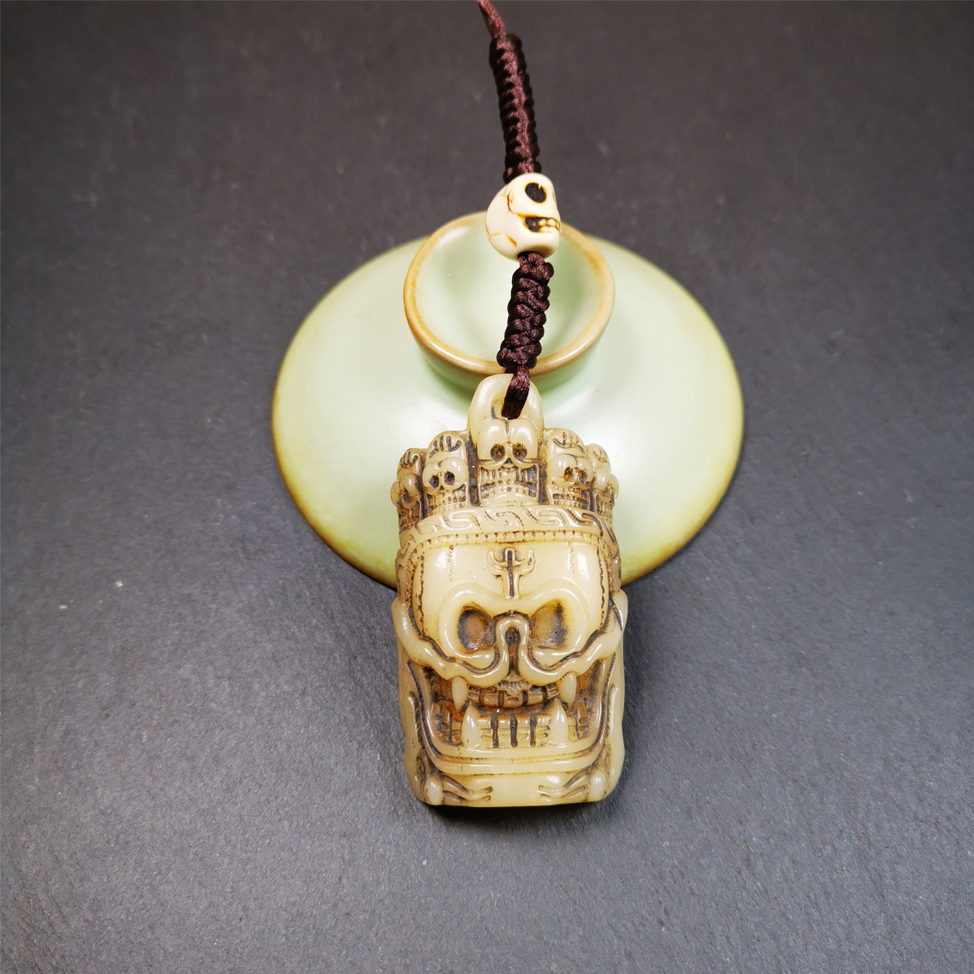 This beautiful bone skull amulet is hand carved by Tibetan craftsmen from Hepo Town, Baiyu County, the birthplace of the famous Tibetan handicrafts. It is Masters of Sitavana, entirely hand-carved of yak bone,wears a crown with 5 skulls,size is 2.3 inches,very beautiful. You can use it as a pendant, or bag hanging,or put it into your shrin