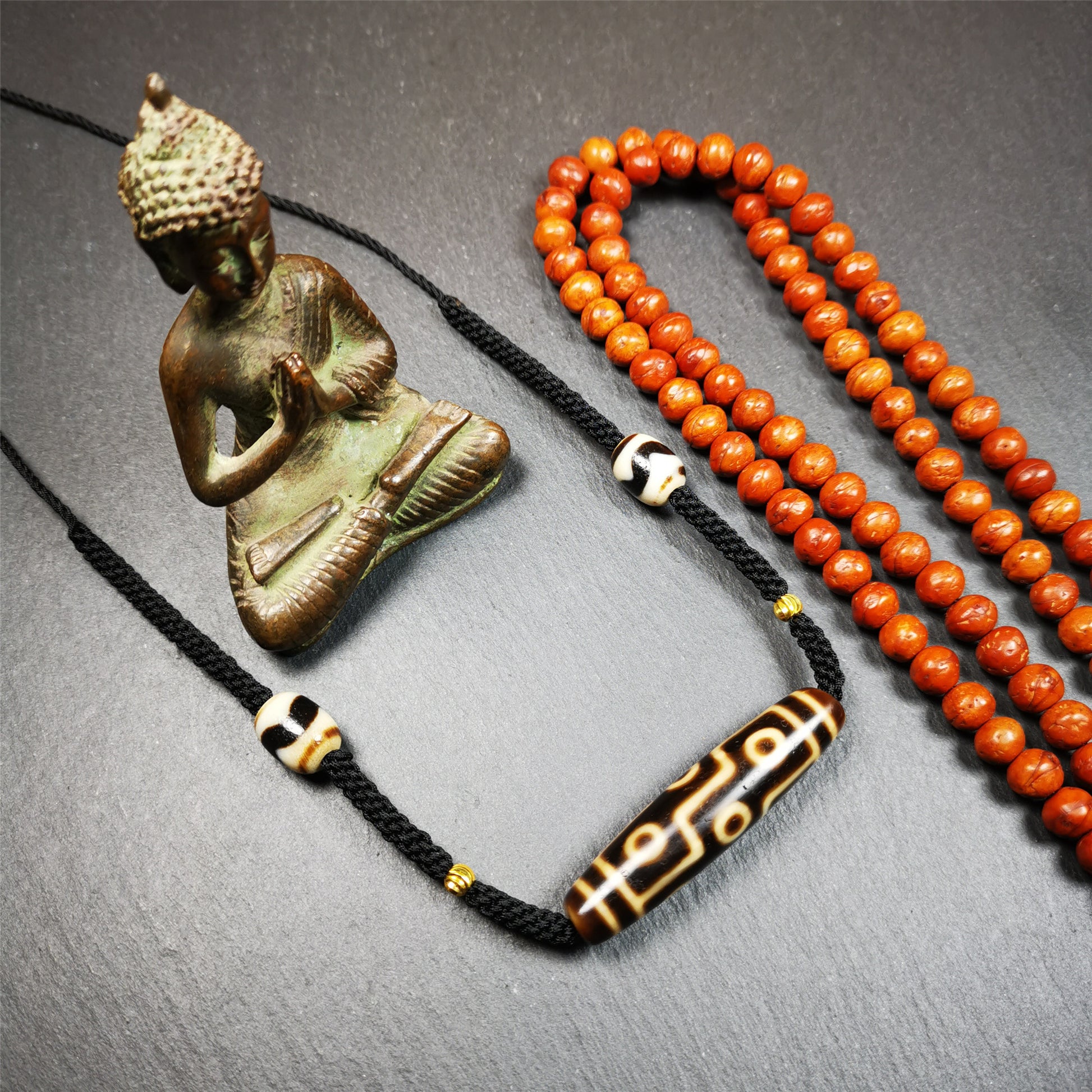 This necklace was hand-woven by Tibetans from Baiyu County, the main bead is a 9 eyed  dzi bead, paired with 2 small tiger tooth dzi beads,about 30 years old. It can be worn as a fashionable accessory,holds cultural and religious significance.