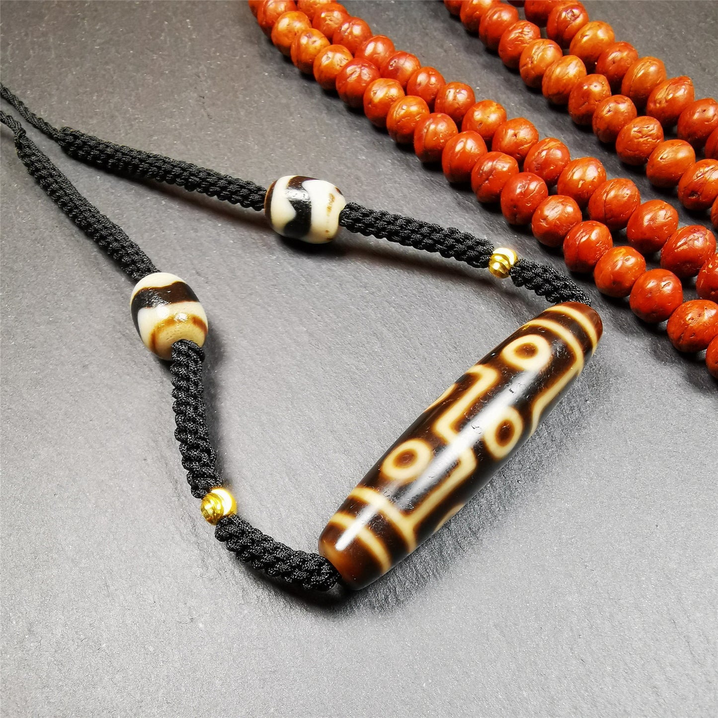 This necklace was hand-woven by Tibetans from Baiyu County, the main bead is a 9 eyed  dzi bead, paired with 2 small tiger tooth dzi beads,about 30 years old. It can be worn as a fashionable accessory,holds cultural and religious significance.