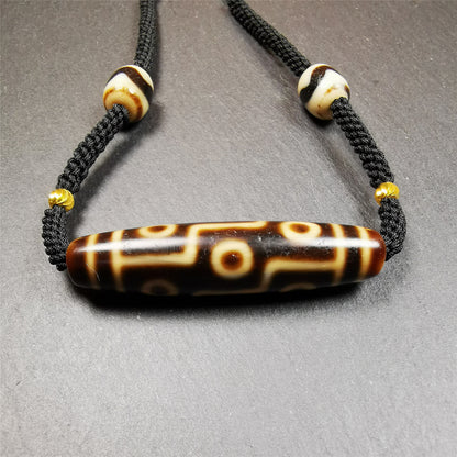 This necklace was hand-woven by Tibetans from Baiyu County, the main bead is a 9 eyed  dzi bead, paired with 2 small tiger tooth dzi beads,about 30 years old. It can be worn as a fashionable accessory,holds cultural and religious significance.