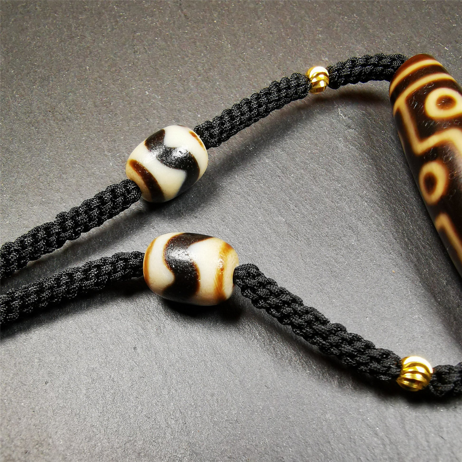 This necklace was hand-woven by Tibetans from Baiyu County, the main bead is a 9 eyed  dzi bead, paired with 2 small tiger tooth dzi beads,about 30 years old. It can be worn as a fashionable accessory,holds cultural and religious significance.