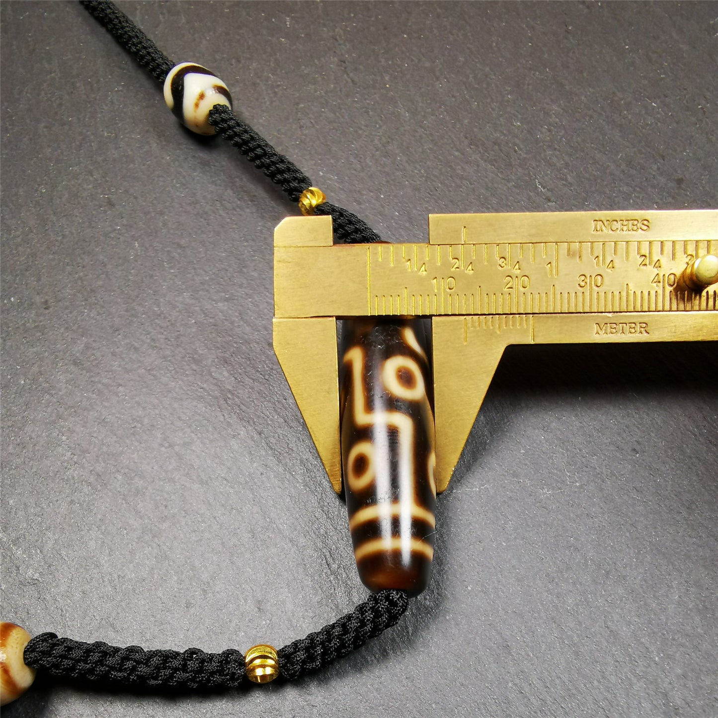This necklace was hand-woven by Tibetans from Baiyu County, the main bead is a 9 eyed  dzi bead, paired with 2 small tiger tooth dzi beads,about 30 years old. It can be worn as a fashionable accessory,holds cultural and religious significance.