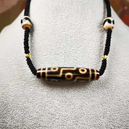 This necklace was hand-woven by Tibetans from Baiyu County, the main bead is a 9 eyed  dzi bead, paired with 2 small tiger tooth dzi beads,about 30 years old. It can be worn as a fashionable accessory,holds cultural and religious significance.