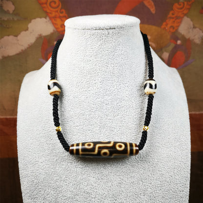 This necklace was hand-woven by Tibetans from Baiyu County, the main bead is a 9 eyed  dzi bead, paired with 2 small tiger tooth dzi beads,about 30 years old. It can be worn as a fashionable accessory,holds cultural and religious significance.