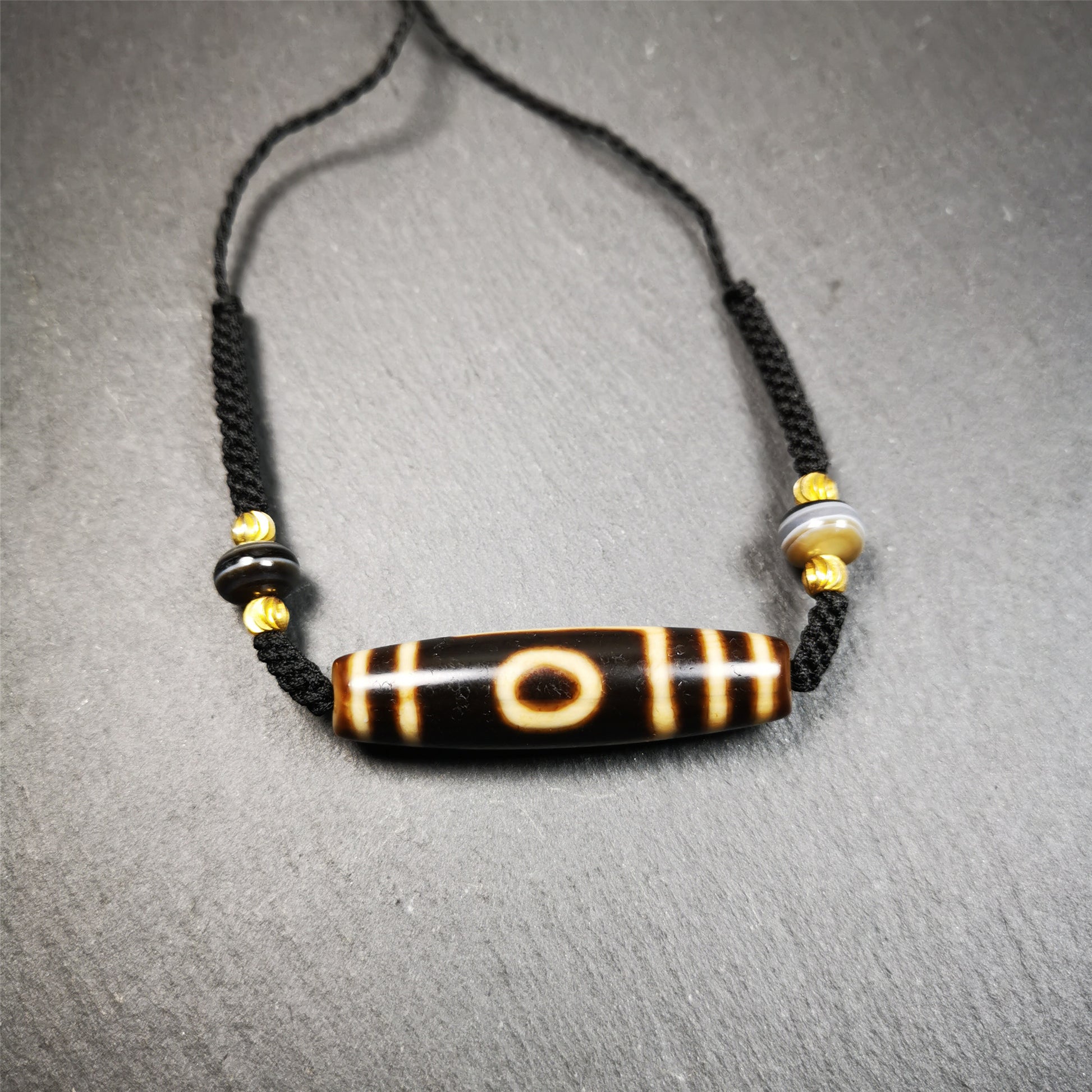 This necklace was hand-woven by Tibetans from Baiyu County, the main bead is a mountain eye dzi bead, paired with 2 small stripe dzi beads,about 30 years old. It can be worn not only as a fashionable accessory but also holds cultural and religious significance.