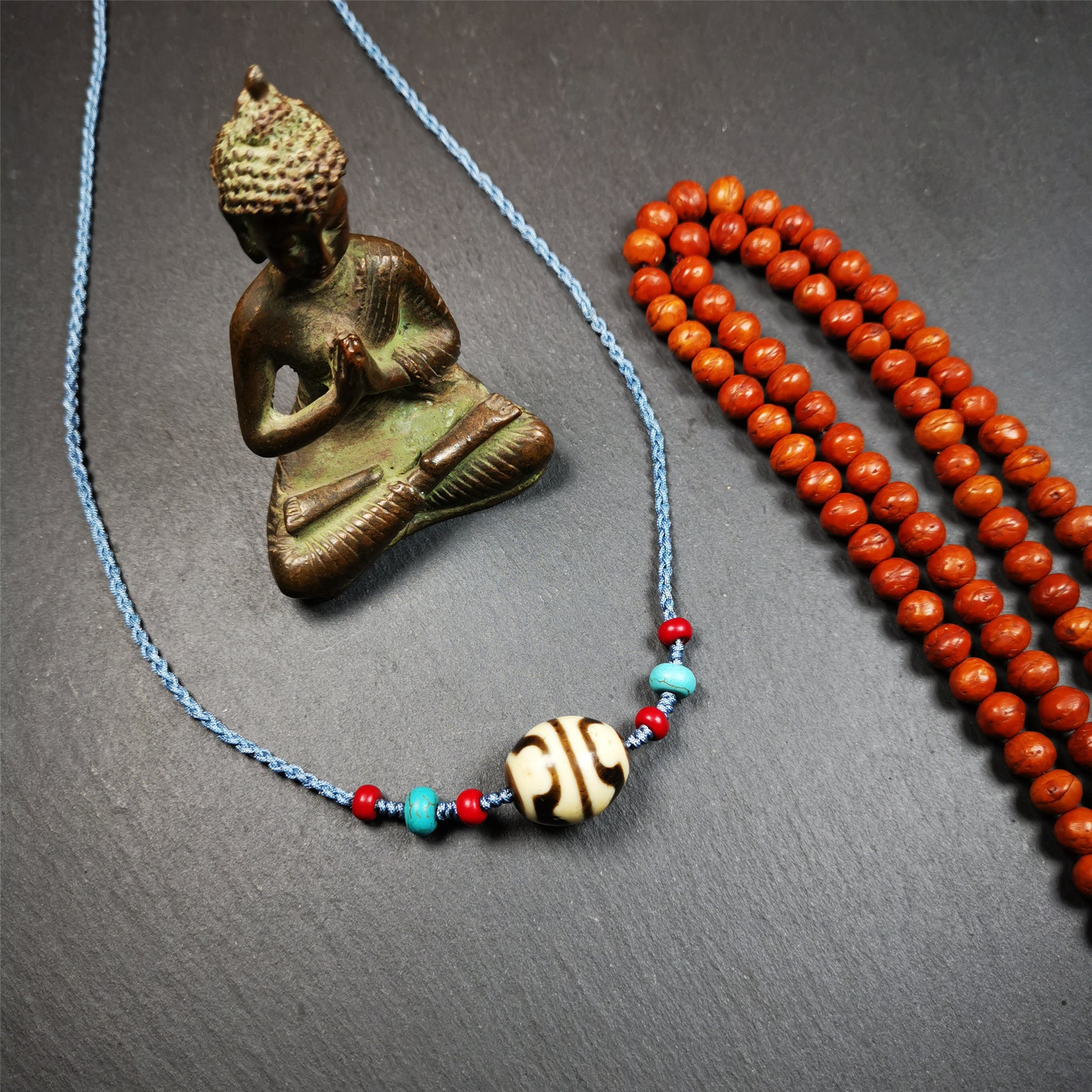 This necklace was hand-woven by Tibetans from Baiyu County, the main bead is a lotus dalo dzi bead, paired with turquoise and agate beads,about 40 years old. It can be worn not only as a fashionable accessory but also holds cultural and religious significance. The length of the necklace can be adjusted, the maximum circumference is about 60cm.