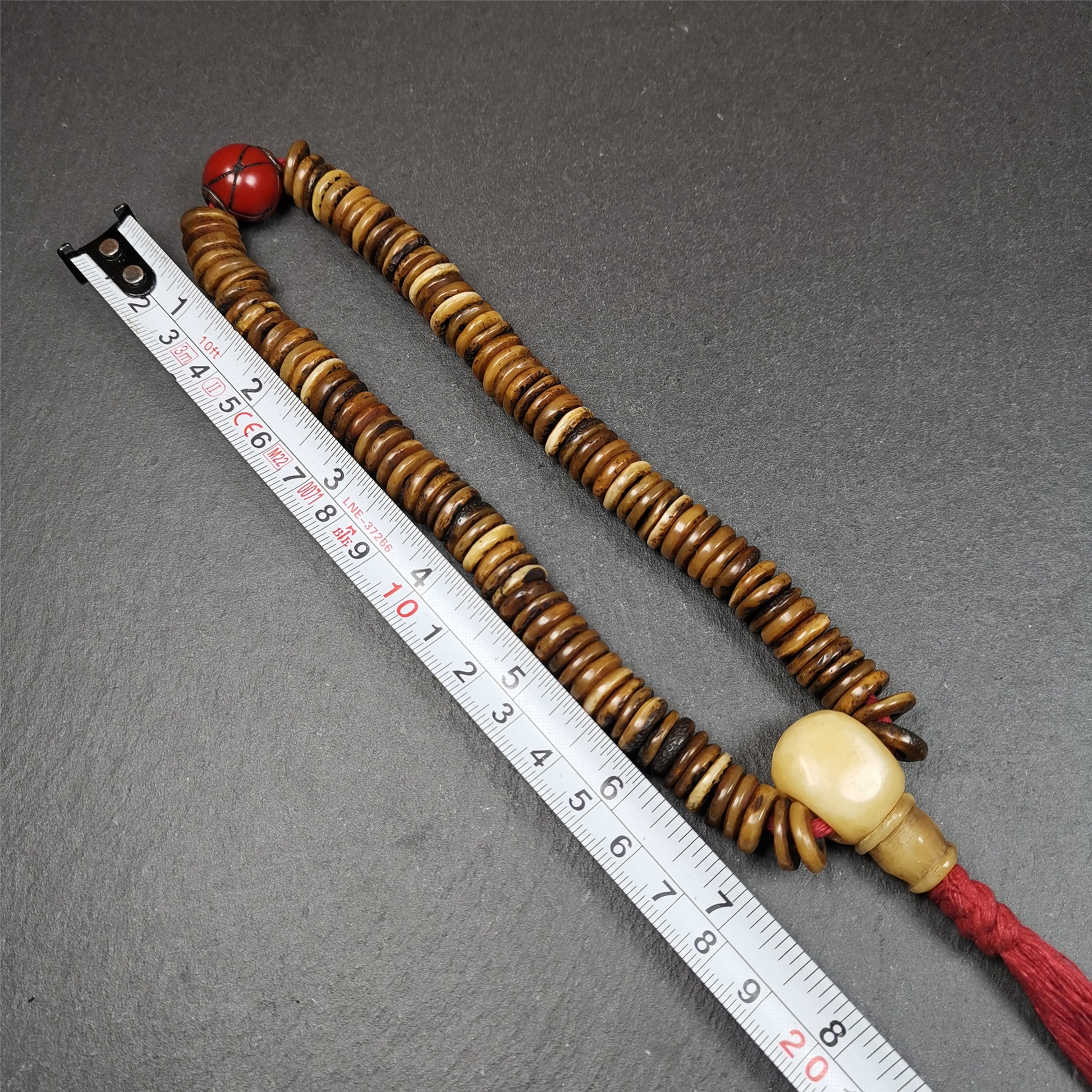 This bone carved mala beads is made by Tibetan craftsmen,about 30 years Old. It has 108 flat shape beads,1 red plastic spacer bead,and 1 yak bone guru bead,all hand carved,diameter is 12mm and perimeter is 15".