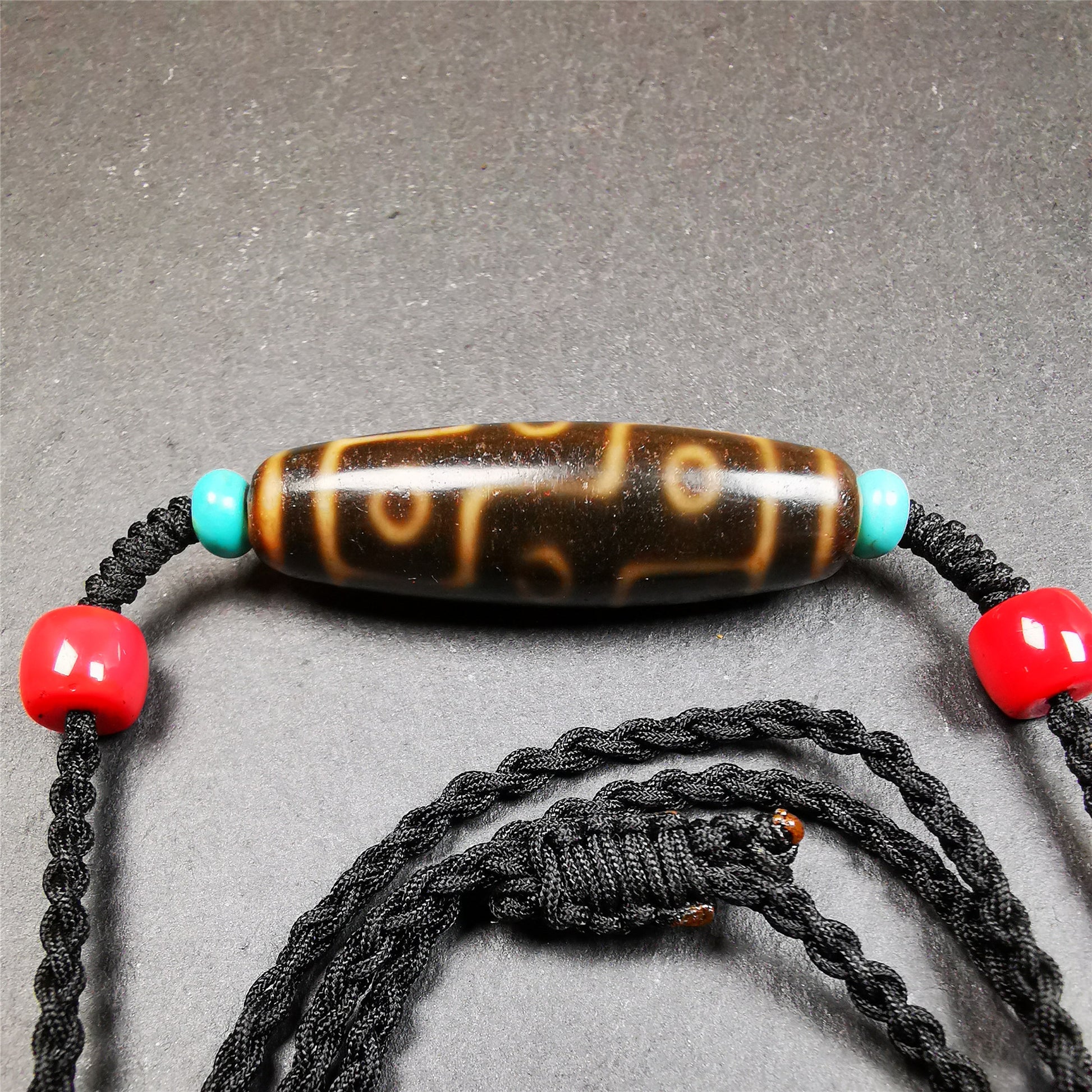 This 9 eyes dzi bead was collected from gerze Tibet,about 50 years old. The necklace was hand-woven by Tibetans from Baiyu County, the main bead is a brown color 9 eyes dzi, paired with 2 turquoise beads and 2 red agate beads.