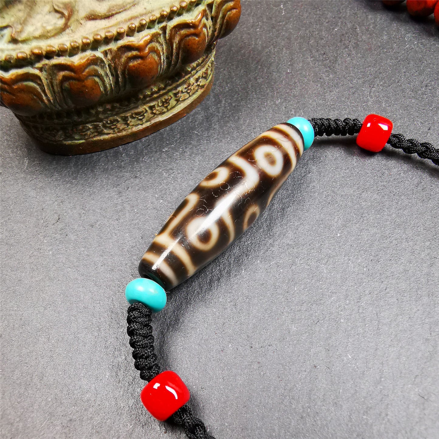 This 9 eyes dzi bead was collected from gerze Tibet,about 40 years old. The necklace was hand-woven by Tibetans from Baiyu County, the main bead is a brown color 9 eyes dzi, paired with 2 turquoise beads and 2 red agate beads.