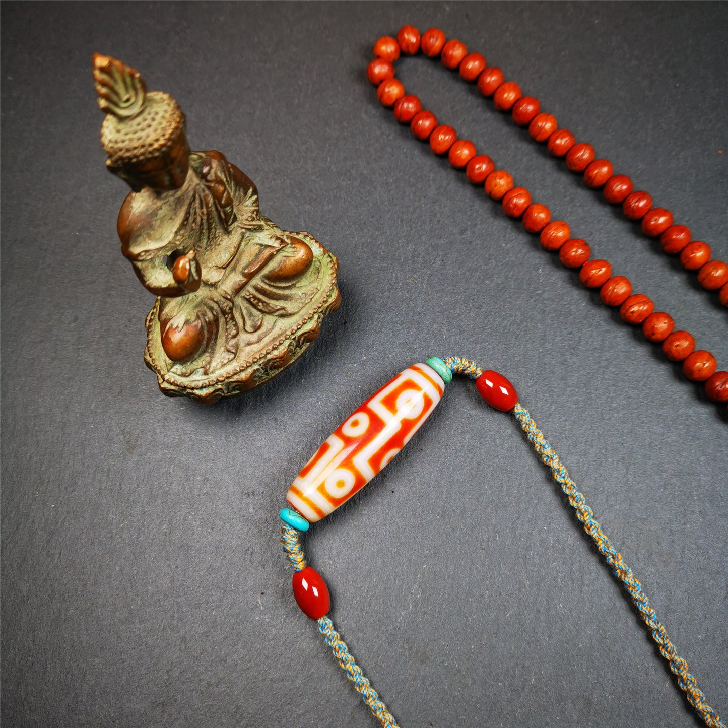 This necklace was hand-woven by Tibetans from Baiyu County, the main bead is a fire agate 9 eyes dzi, paired with 2 turquoise beads and 2 red agate beads,about 30 years old. The length of the necklace can be adjusted, the maximum circumference is about 60cm.