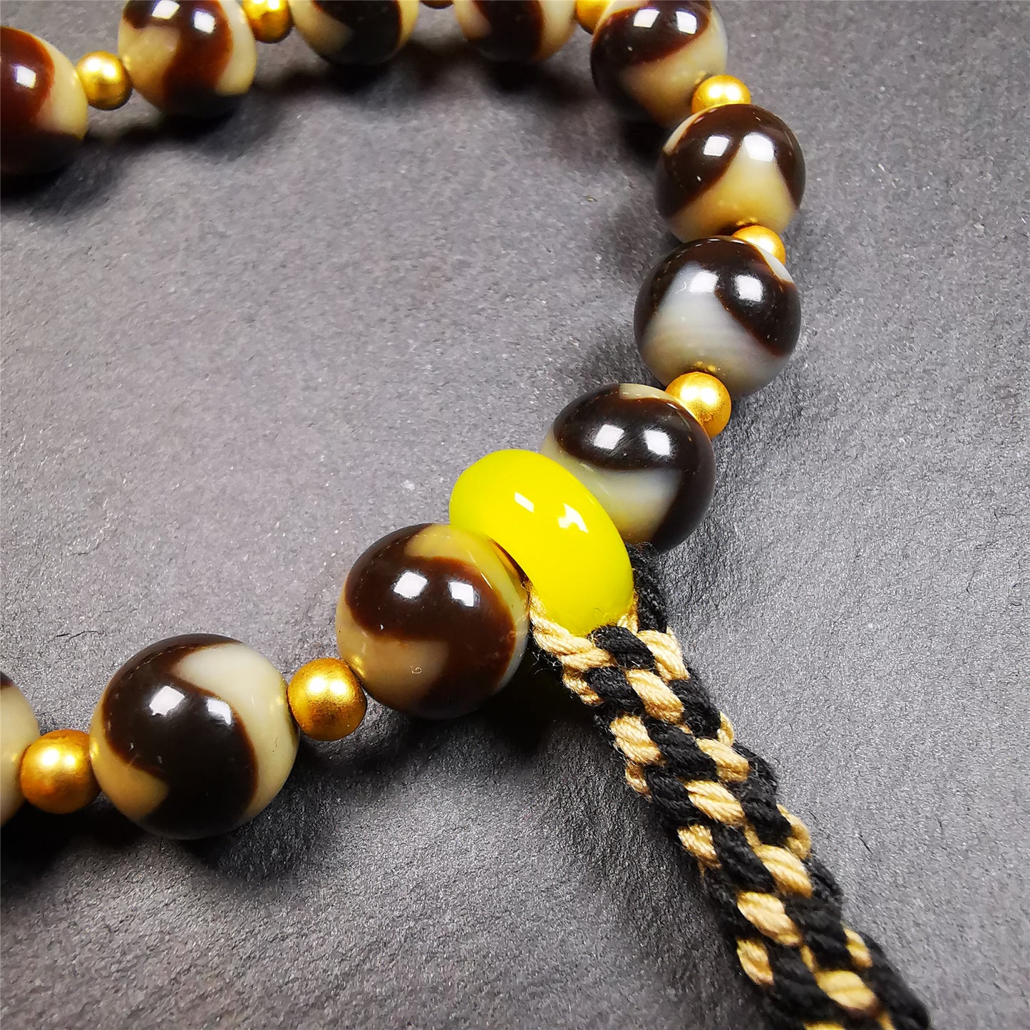 This tiger tooth dzi bracelet was hand-woven by Tibetans from Baiyu County,Tibet. It consists of 15 tiger tooth dzi beads and 15 spacer beads,tie with elastic cord to fit your wrist.  Dzi beads are precious jewelry from Tibetan culture which are believed to possess the power of bringing good fortune to the owners.  You'll get 1 dzi bracelet as pictures shown.