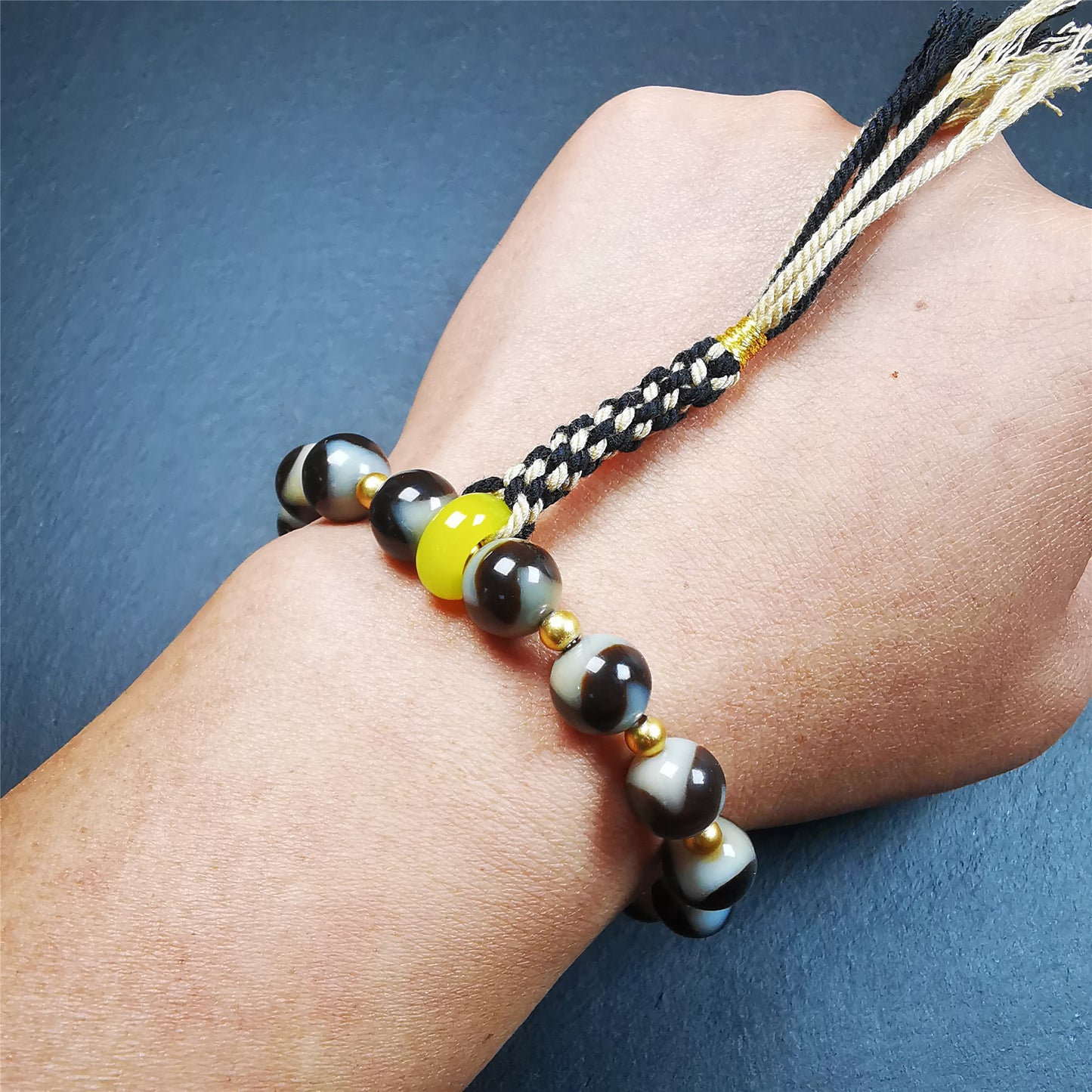 This tiger tooth dzi bracelet was hand-woven by Tibetans from Baiyu County,Tibet. It consists of 15 tiger tooth dzi beads and 15 spacer beads,tie with elastic cord to fit your wrist.  Dzi beads are precious jewelry from Tibetan culture which are believed to possess the power of bringing good fortune to the owners.  You'll get 1 dzi bracelet as pictures shown.