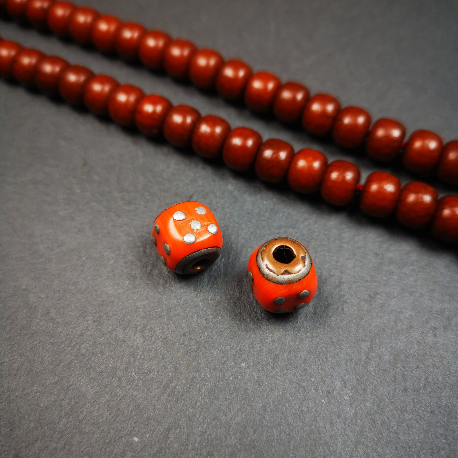 These marker beads were handmade by Tibetan craftsmen and come from Hepo Town, Baiyu County, the birthplace of the famous Tibetan handicrafts. It is made of plastic,inlaid cold iron,orange color,size is 0.47" × 0.47". Fit for 8-12mm mala (The reference in the photo is 8mm mala)