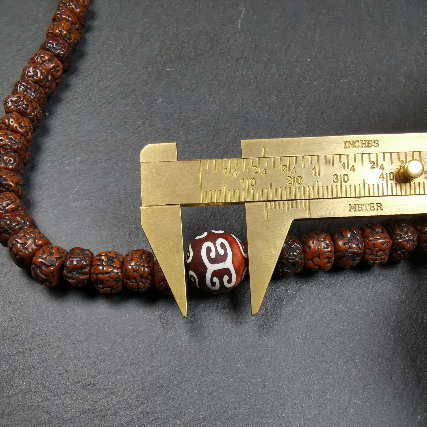 This old mala was handmade from tibetan crafts man in Baiyu County,blessed in Baiyu monastery. It's composed of 108 pcs 9mm rudraksha beads,with 3 cloud patter dzi beads,bead diameter is 0.35 inch and circumference is 30 inches.
