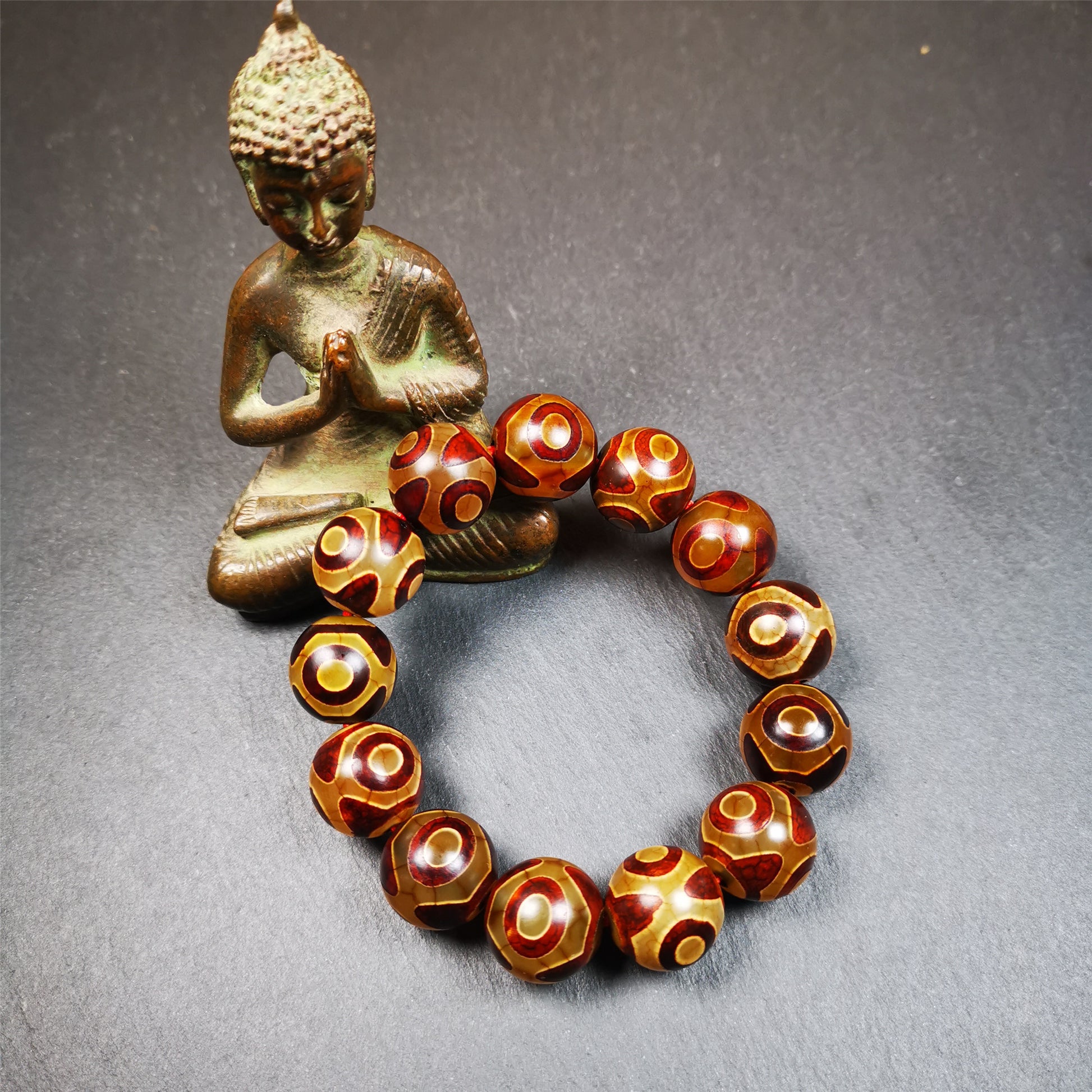  This 3 eyes bracelet was hand-woven by Tibetans,It's made of 3 eyes round dzi beads,brown color,diameter is 0.63", the circumference of bracelet is 7.5".  It can be worn not only as a fashionable accessory but also holds cultural and religious significance.